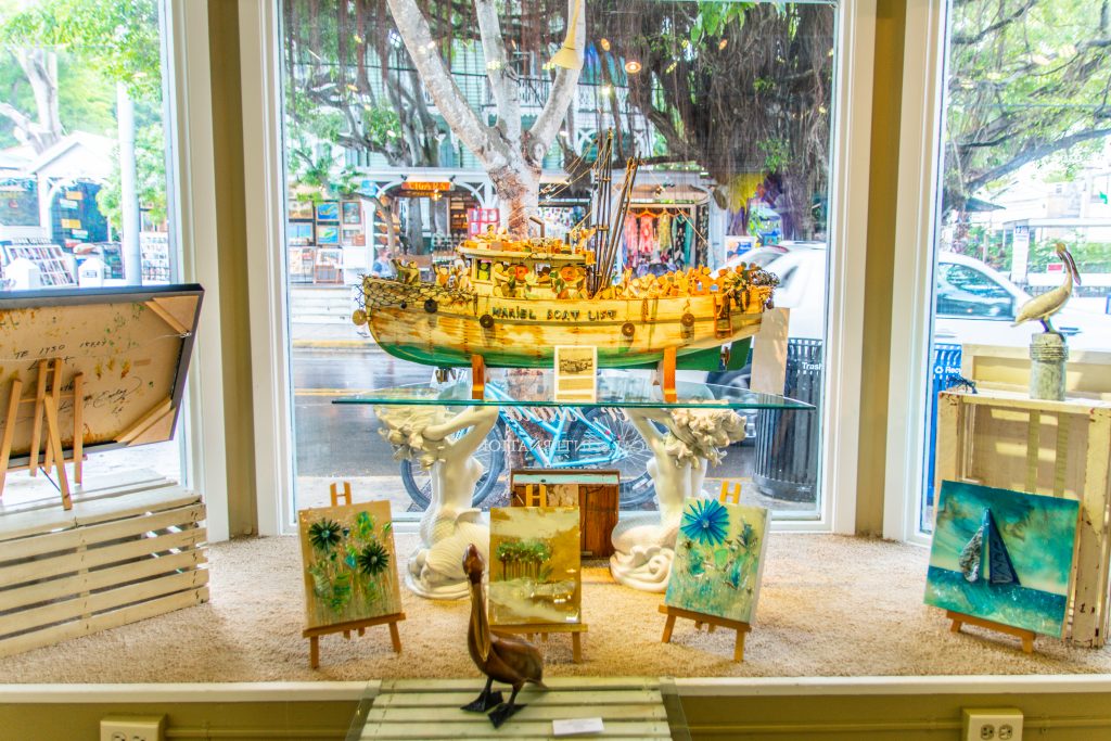 A painting of a boat on display in the window.