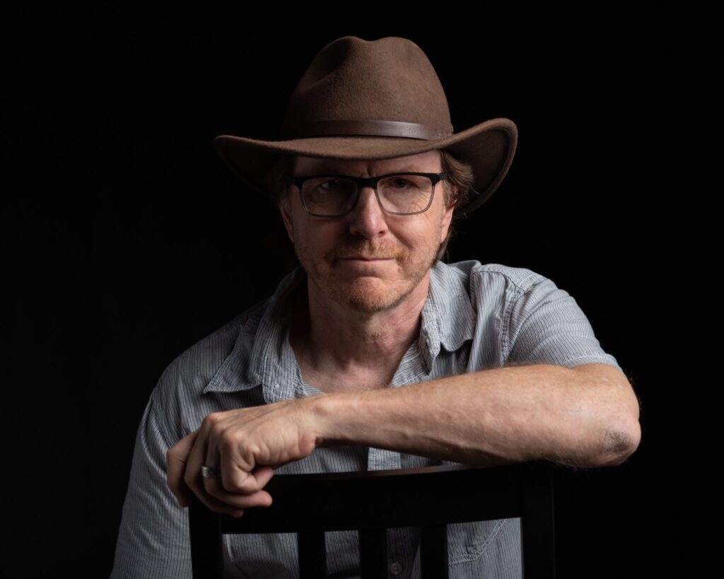 A man in a hat sitting on top of a chair.