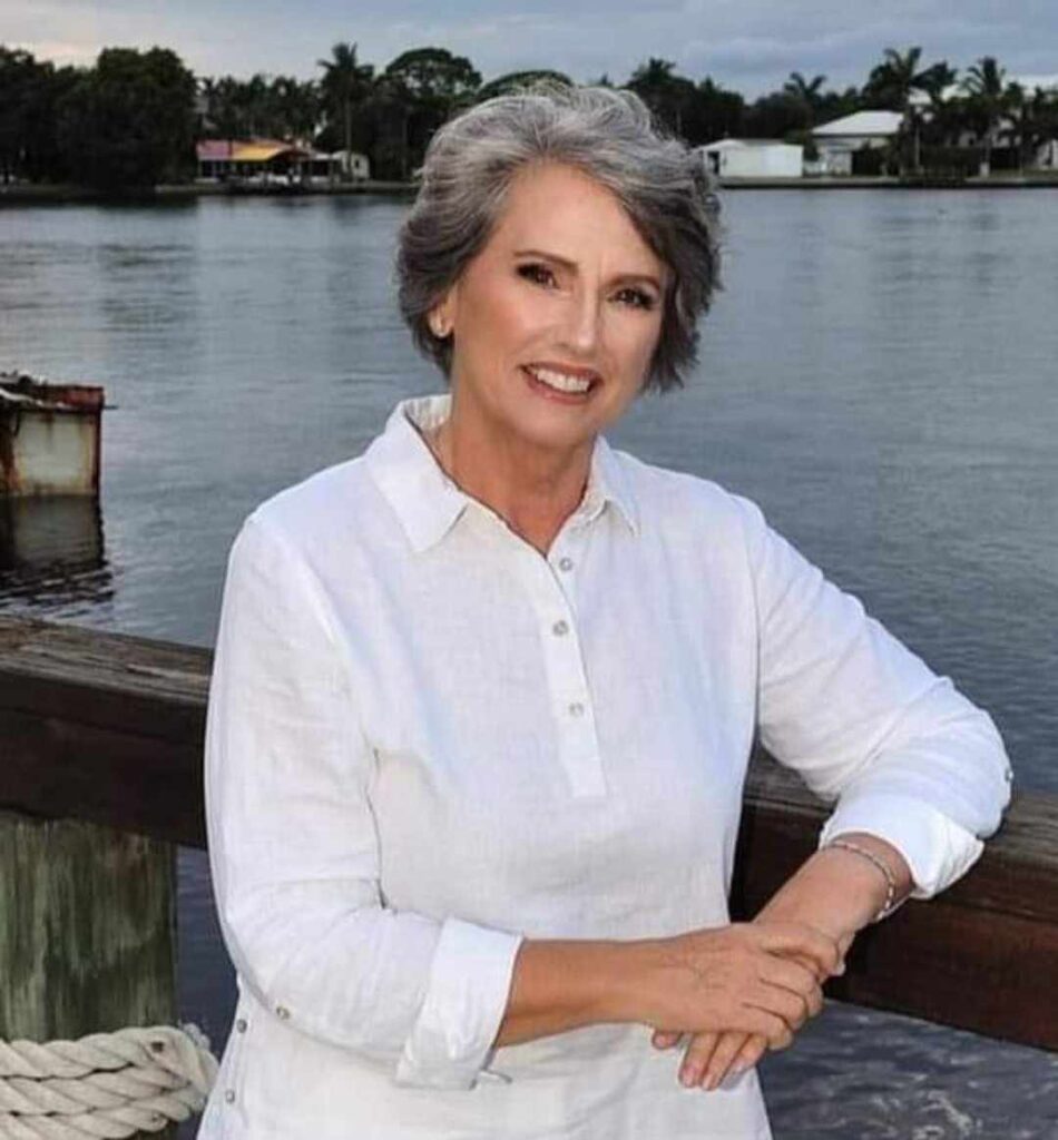 A woman in white shirt standing next to water.